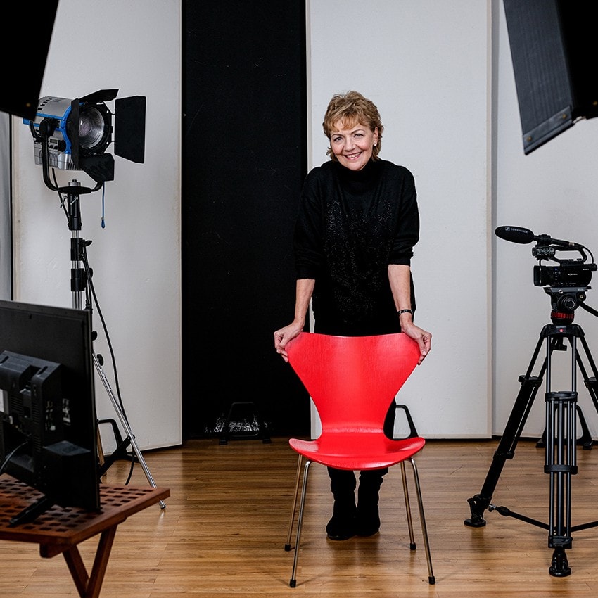 Renate Starke im Studio hinter einem roten Stuhl, zwischen Kamera und Scheinwerfern